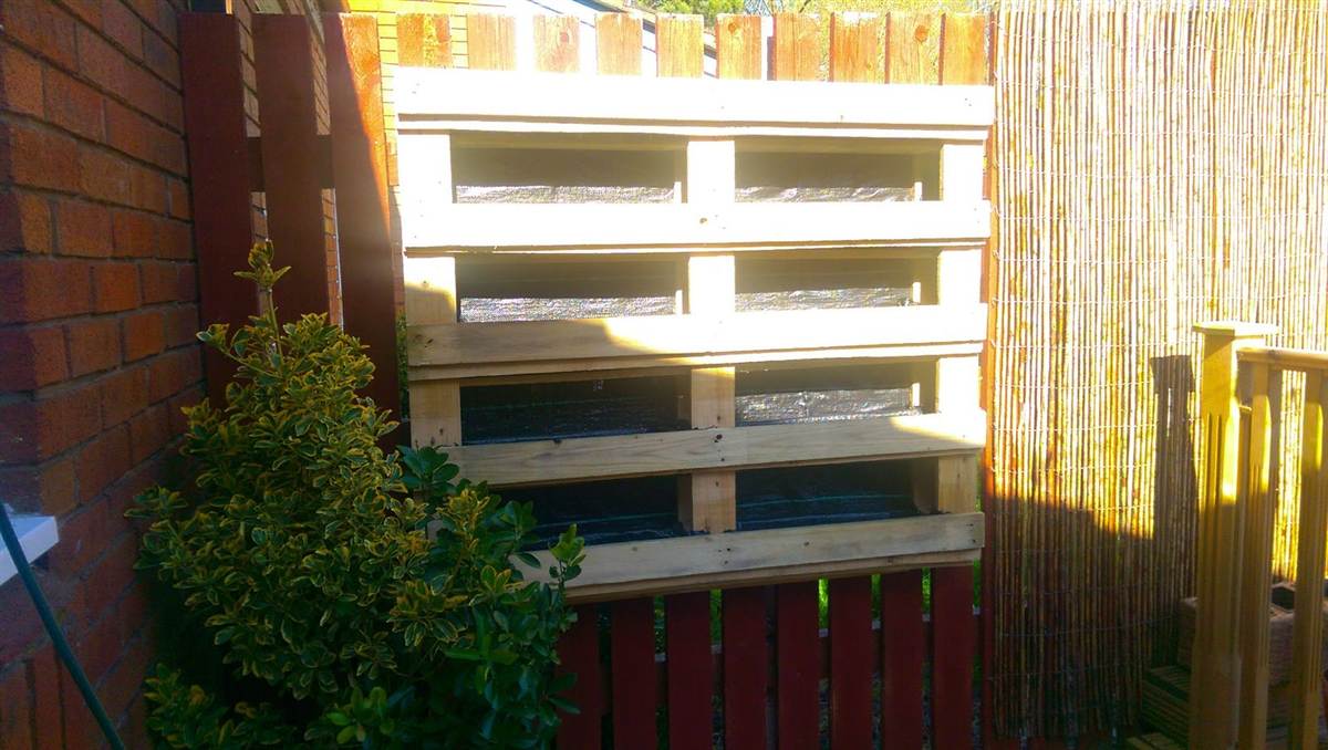Pallet planter frame built, painted and mounted on the fence with liner fitted in each tier, not yet planted